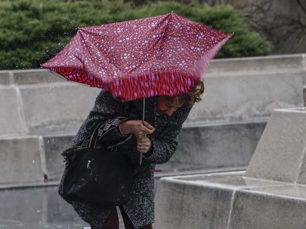 Una mujer intenta controlar su paraguas en medio de una tormenta en Madrid. (EFE/Sergio Pérez).