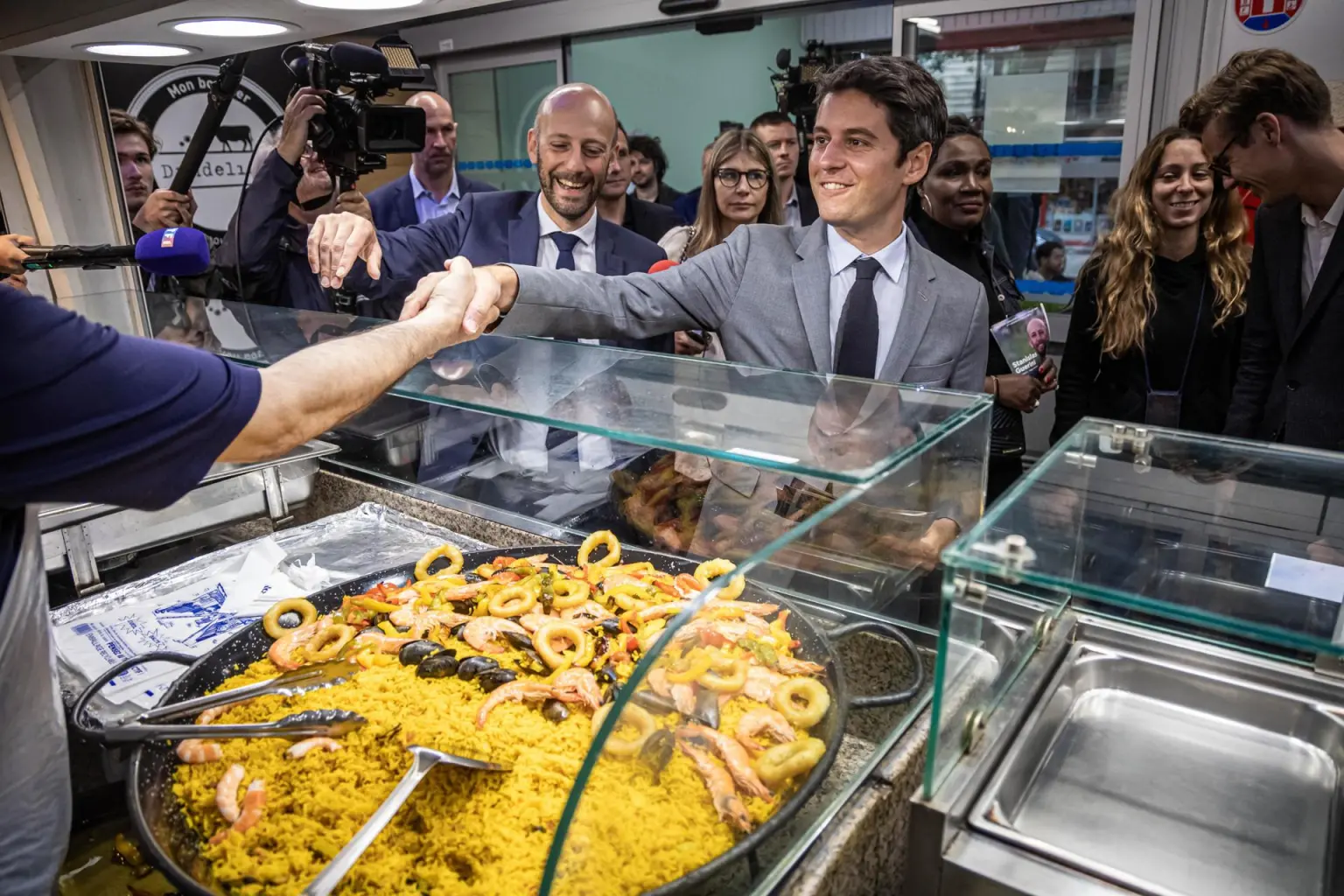 El primer Ministro francés Gabriel Attal (C) visita un mercado de alimentos con el candidato del partido mayoritario presidencial. EFE//CHRISTOPHE PETIT TESSON