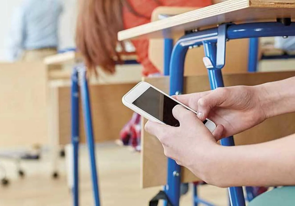 Estudiante usando el móvil de incógnito en el aula